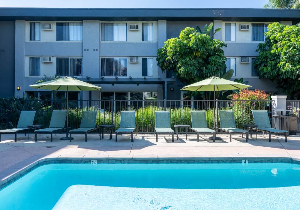 Swimming pool with lounge beds at UCE Apartment Homes in Fullerton, California  