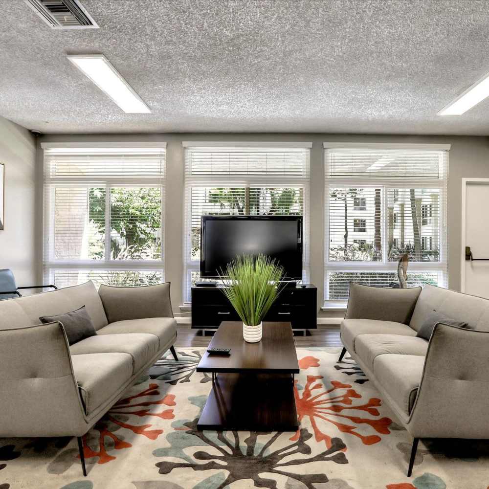 Community clubhouse with large couch, coffee table and flat screen television at Santa Teresa Apartments in San Jose, California