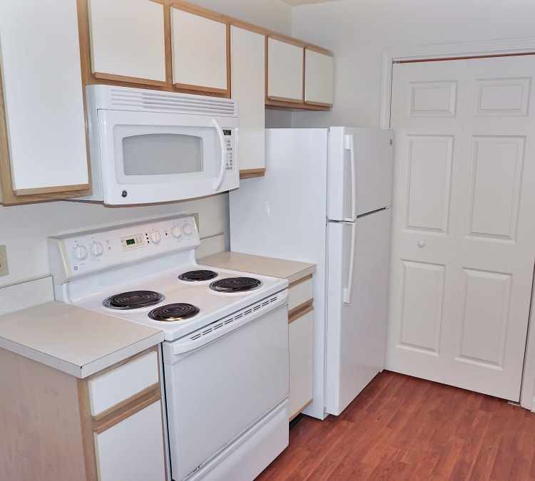 Modern kitchen with white appliances and hardwood floors in model home at Renaissance St. Andrews in Louisville, Kentucky