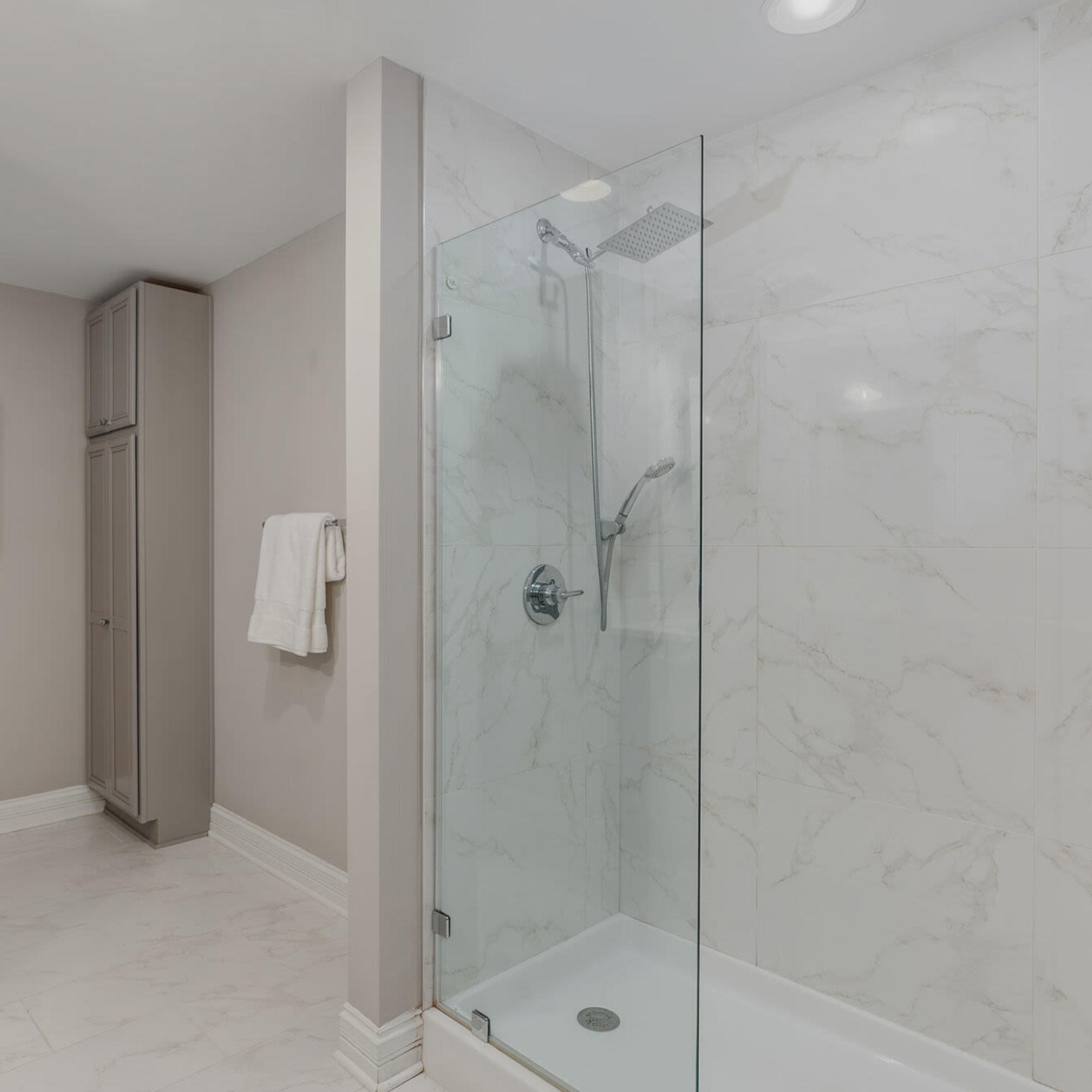 Sleek glass shower with elegant marble tiles and modern fixtures at LeVeque Tower in Columbus, Ohio