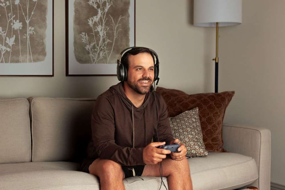 Resident in his living room playing games at The Waters at Promenade in Marrero, Louisiana