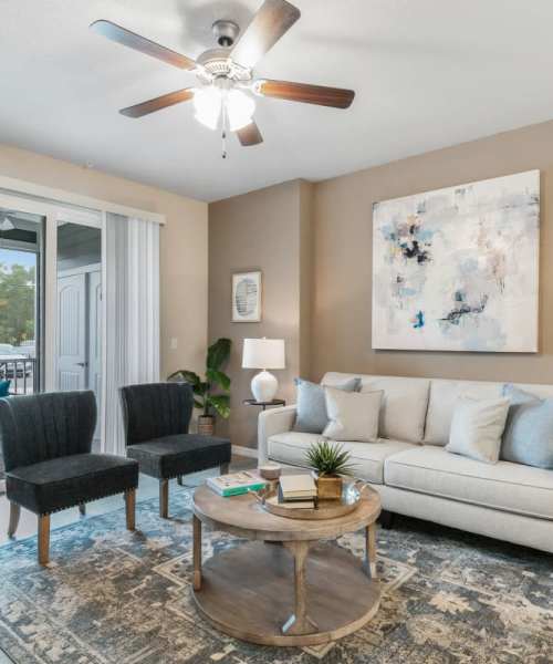 Well-furnished apartment living area with access to the balcony at The Bergamot Apartments On 780 in Sarasota, Florida