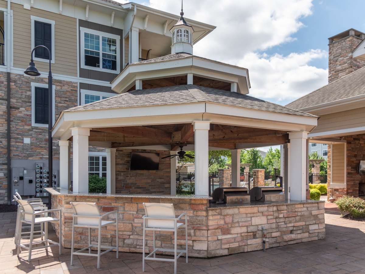 Covered Modern Outdoor Grill Area with TV and Seating at Red Knot at Edinburgh in Chesapeake, Virginia.