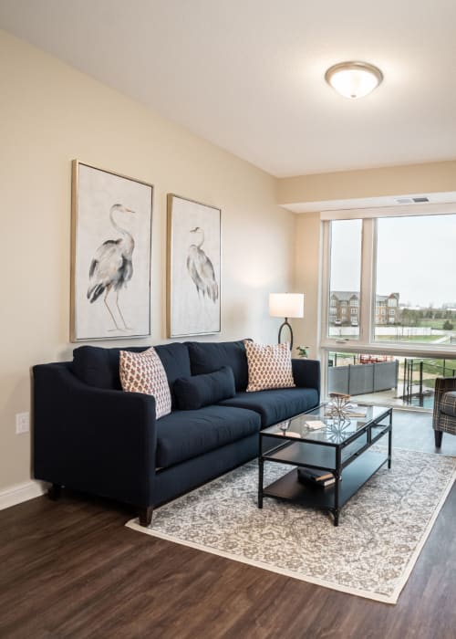 Resident living room with dark hardwood floors and dark blue sofa with plaid armchair at The Pillars of Lakeville in Lakeville, Minnesota