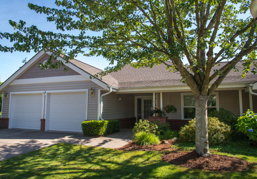 Lovely cottage entrance with a tree and healthy green grass at Touchmark at Fairway Village in Vancouver, Washington