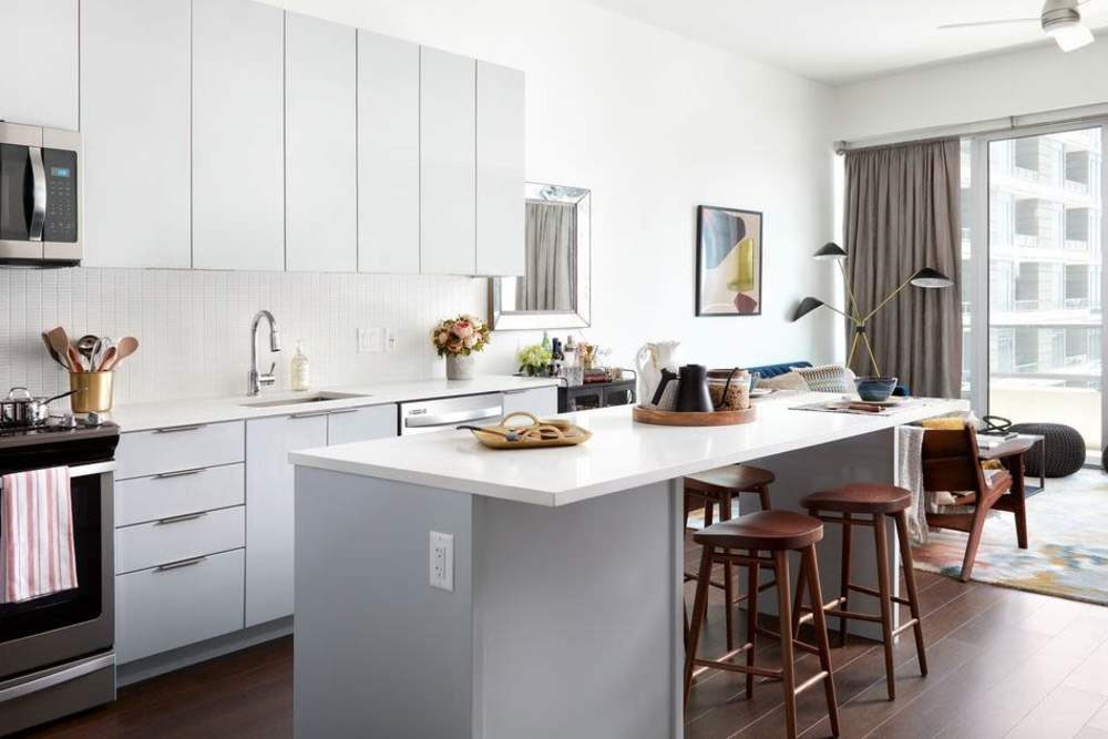 Fully-equipped kitchen with stainless steel appliances and island with bar stools along with entry to patio at Ardan in Dallas, Texas