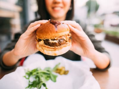 Resident showing a juicy burger at a restaurant near at Auberge of Burleson in Burleson, Texas