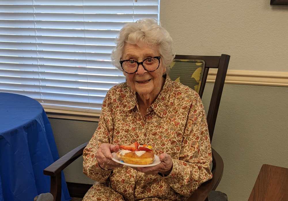 Resident posing with her food in a chair at Truewood by Merrill, Clovis in Clovis, California
