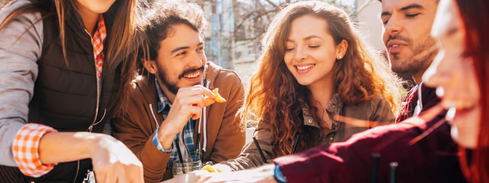 Friends gather for snacks and drinks at an outdoor table near Strata Apartments in Denver, Colorado