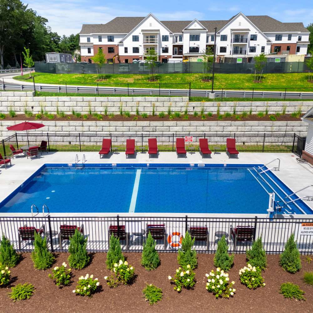 Community pool with sun loungers and apartment buildings in the background at Middleborough Station in Middleborough, Massachusetts