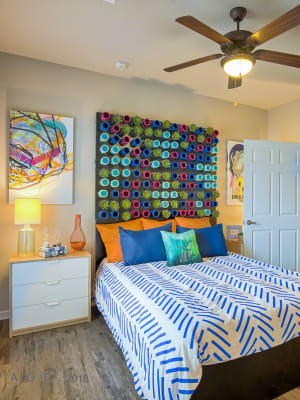 Elegant model master bedroom with hardwood style flooring and a ceiling fan at Creekside at Kenney's Fort in Round Rock, Texas