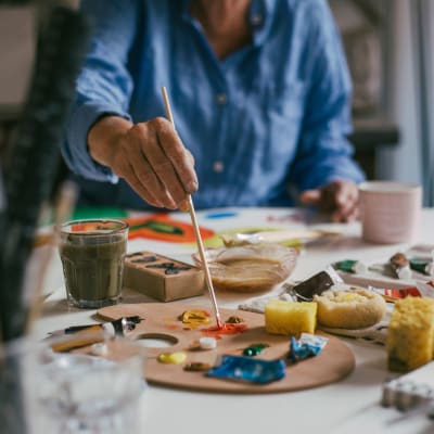 Resident mixing paint in an art class at a senior living community by Cascade Senior Living Services