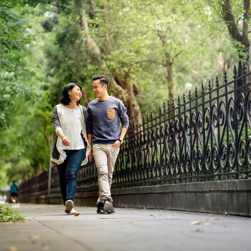 Couple strolling through a tree-lined park near Oaks Braemar in Edina, Minnesota