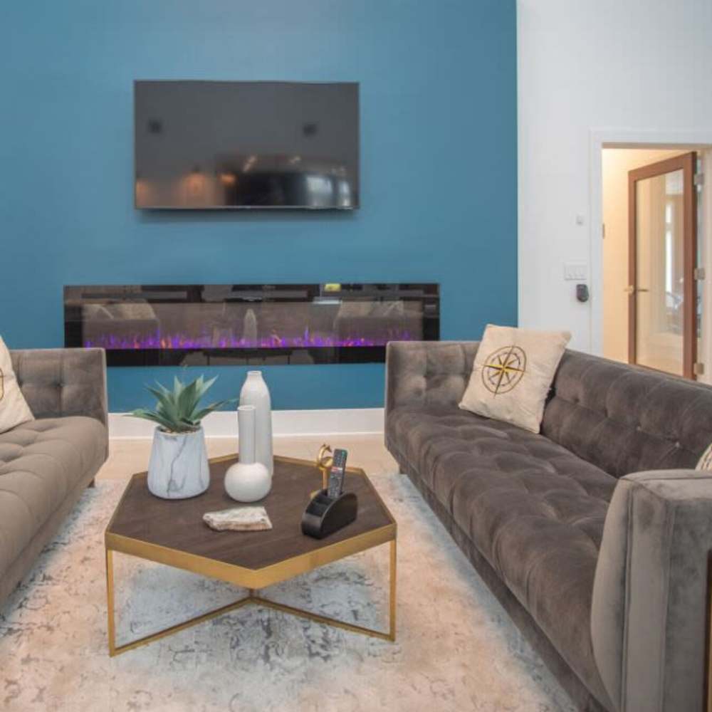 Modern living room with cozy seating and fireplace at The Apartments At Kelton Station in Williamsburg, Virginia