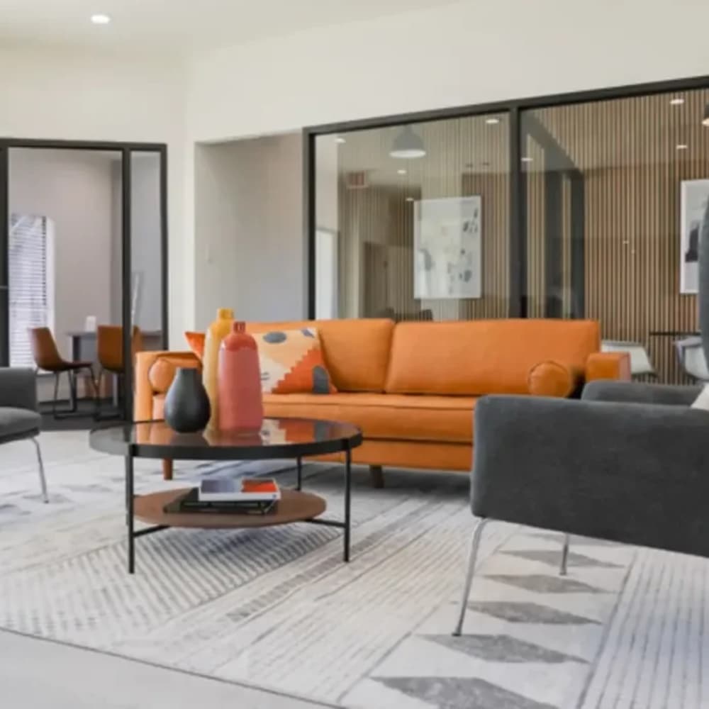 Modern lounge with vibrant orange sofa at The Larsen Apartments in Dallas, Texas