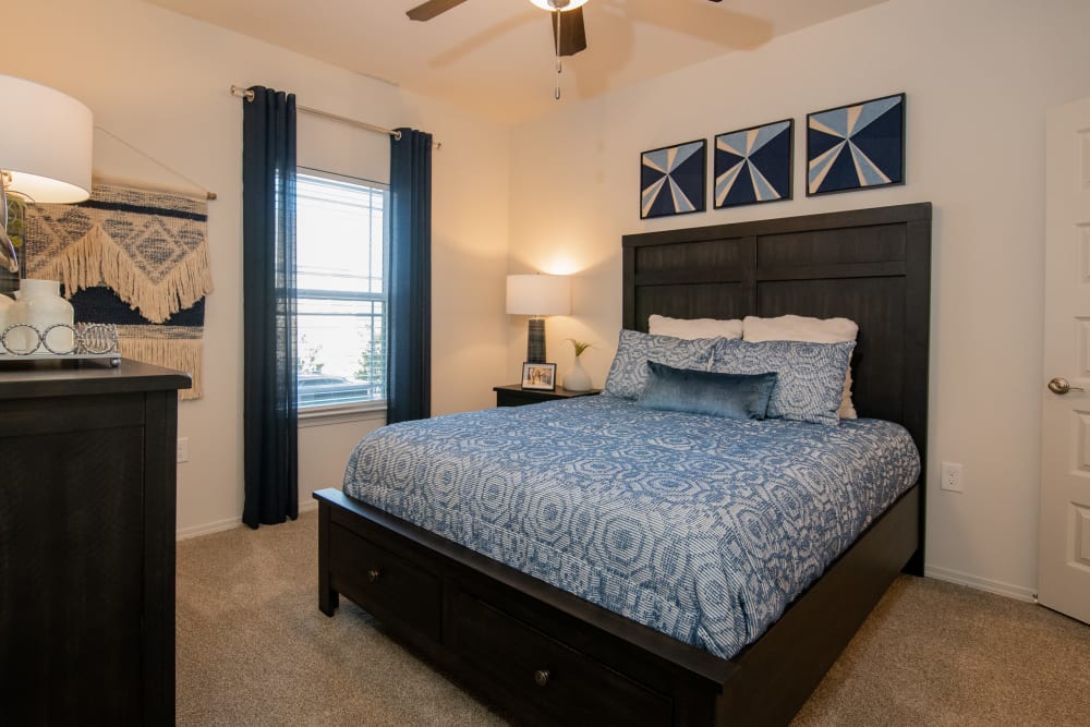 Model bedroom with plush carpeting and ceiling fan at 24Hundred Apartments in Oklahoma City, Oklahoma