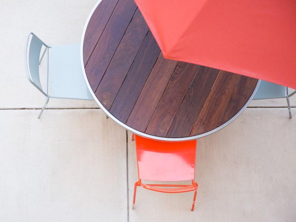 Overhead view of an umbrella providing shade for a table and chairs at Sofi Belmont Glen in Belmont, California