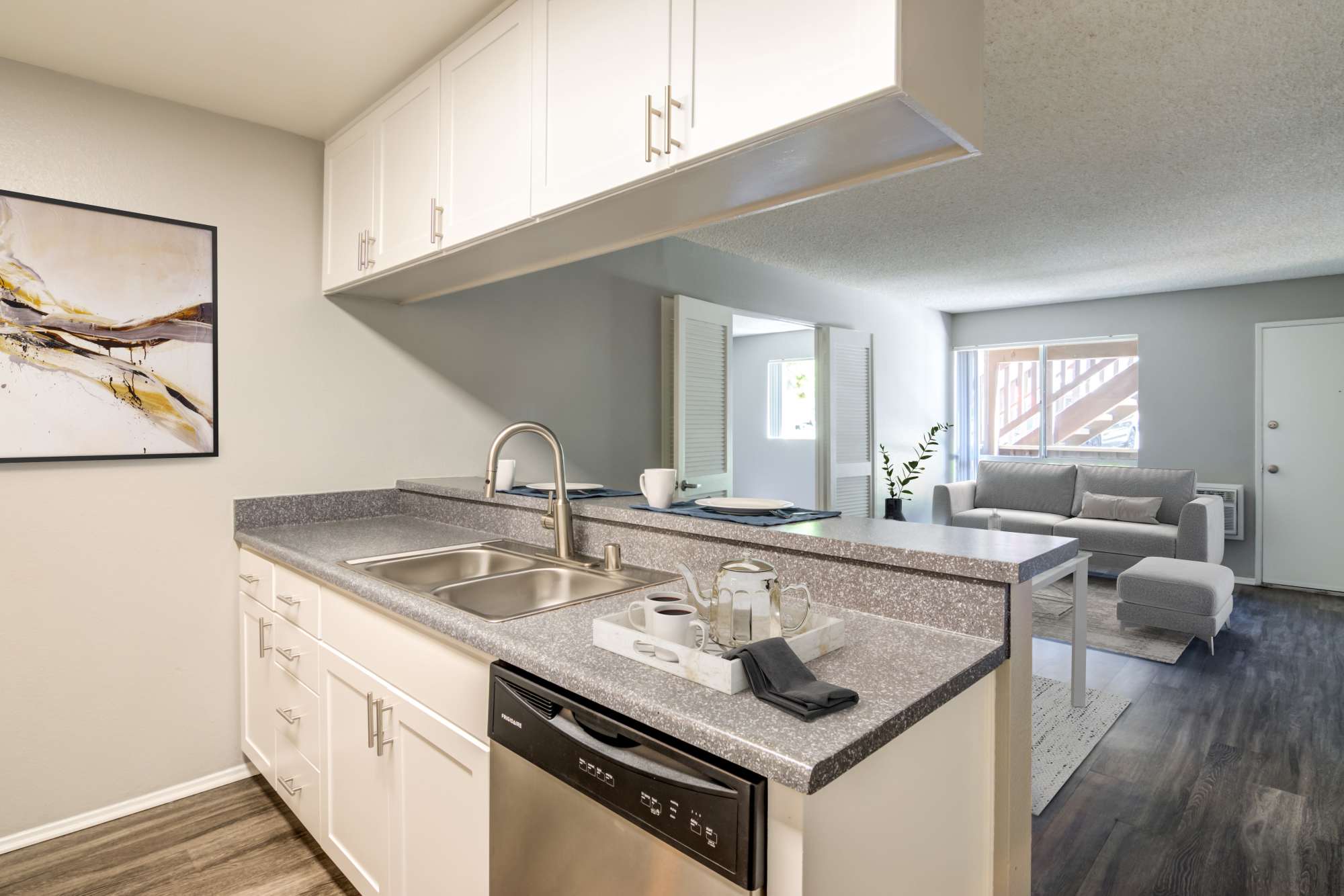 A renovated kitchen with white cabinets overlooking the living room at Hillside Terrace Apartments in Lemon Grove, California