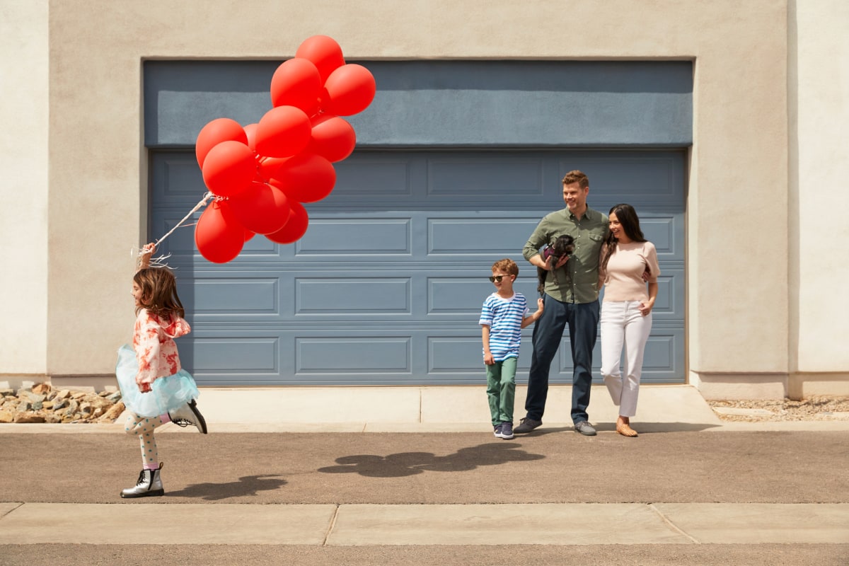 A child holding a bunch of balloons with her family at BB Living at Civic Square in Goodyear, Arizona