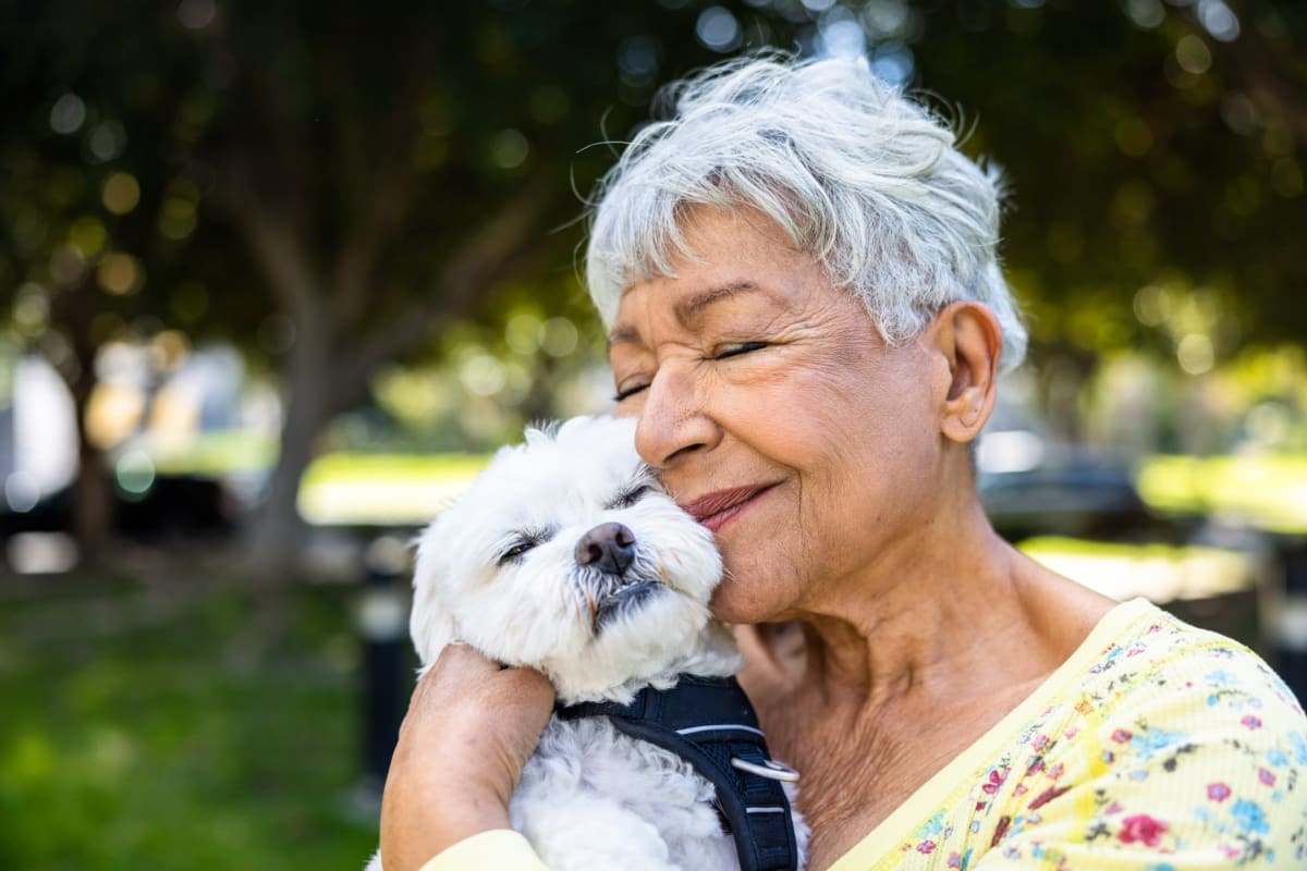 Woman hugging her small white dog outside at Oxford Vista Wichita in Wichita, Kansas