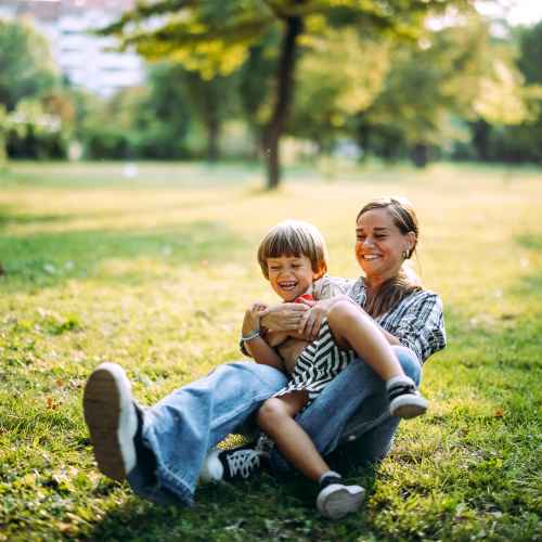 Joyful moments in a sunlit park, laughter and playfulness captured at Messina Luxury Apartments in New Smyrna Beach, Florida