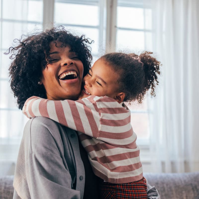 Mother and daughter smile and hug in apartment at Infinity at Centerville Crossing, Virginia Beach, Virginia