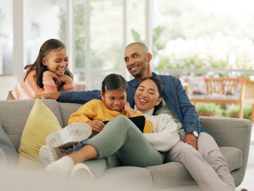 Happy family reading a book in the living room at Viva at New Smyrna Beach in New Smyrna Beach, Florida