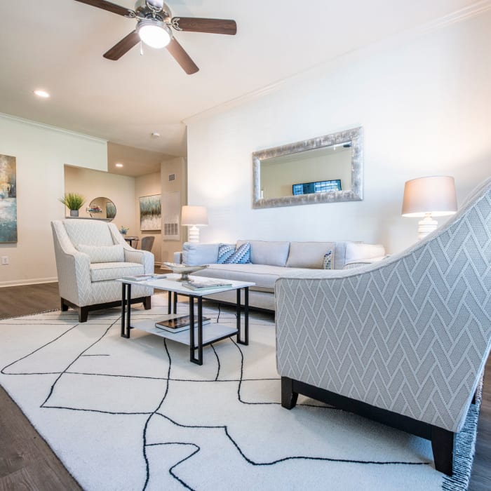 An apartment living room with a couch and arm chairs at The Highland Club in Baton Rouge, Louisiana