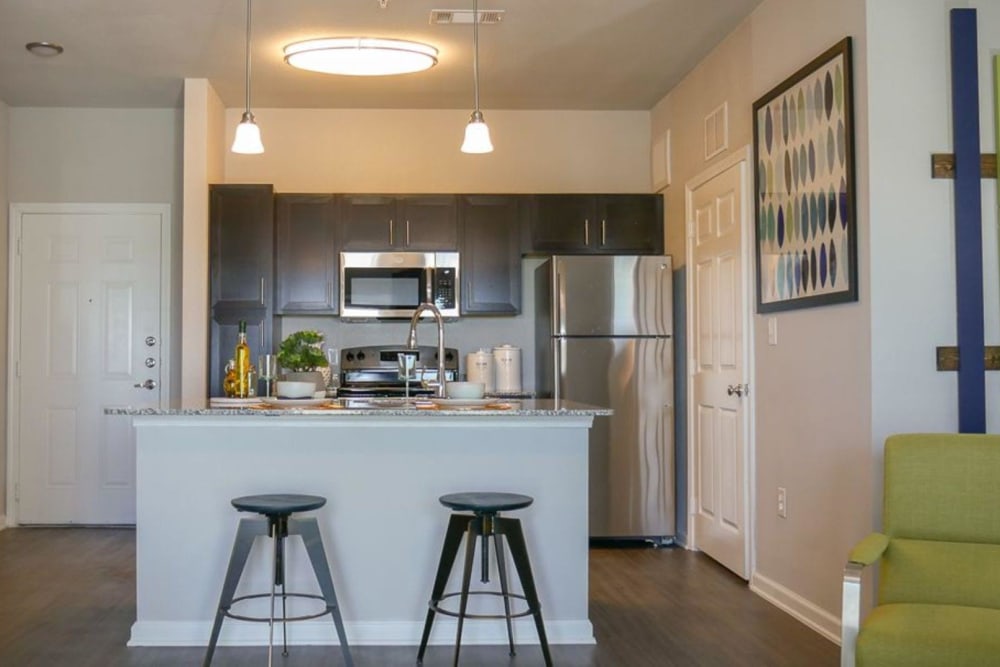 View of the kitchen and island seating from living room at Biltmore at the Park in Pflugerville, Texas