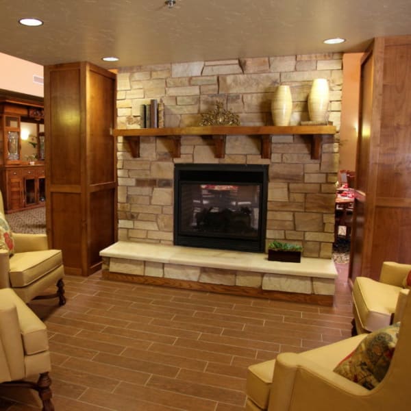 Warmly lit lounge with a fireplace at Quail Park Memory Care Residences of Visalia in Visalia, California