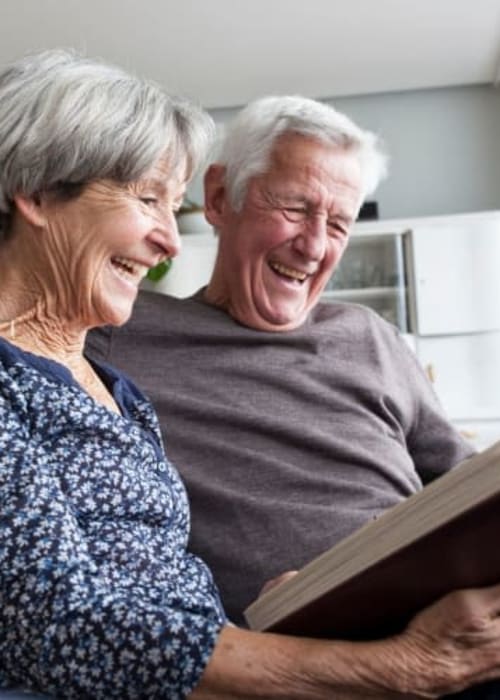 Resident couple looking through photo album at Grand Villa of St. Petersburg in St. Petersburg, Florida