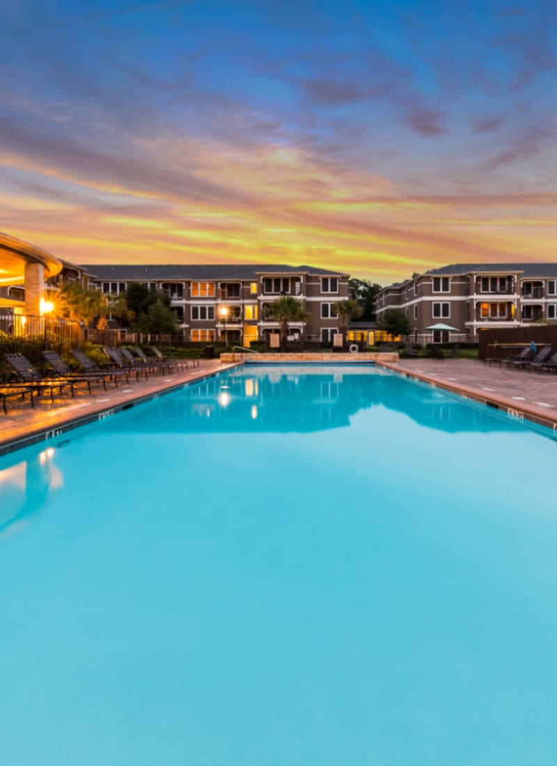 Lighted pool at sunset overlooking units at Marquis at The Cascades in Tyler, Texas