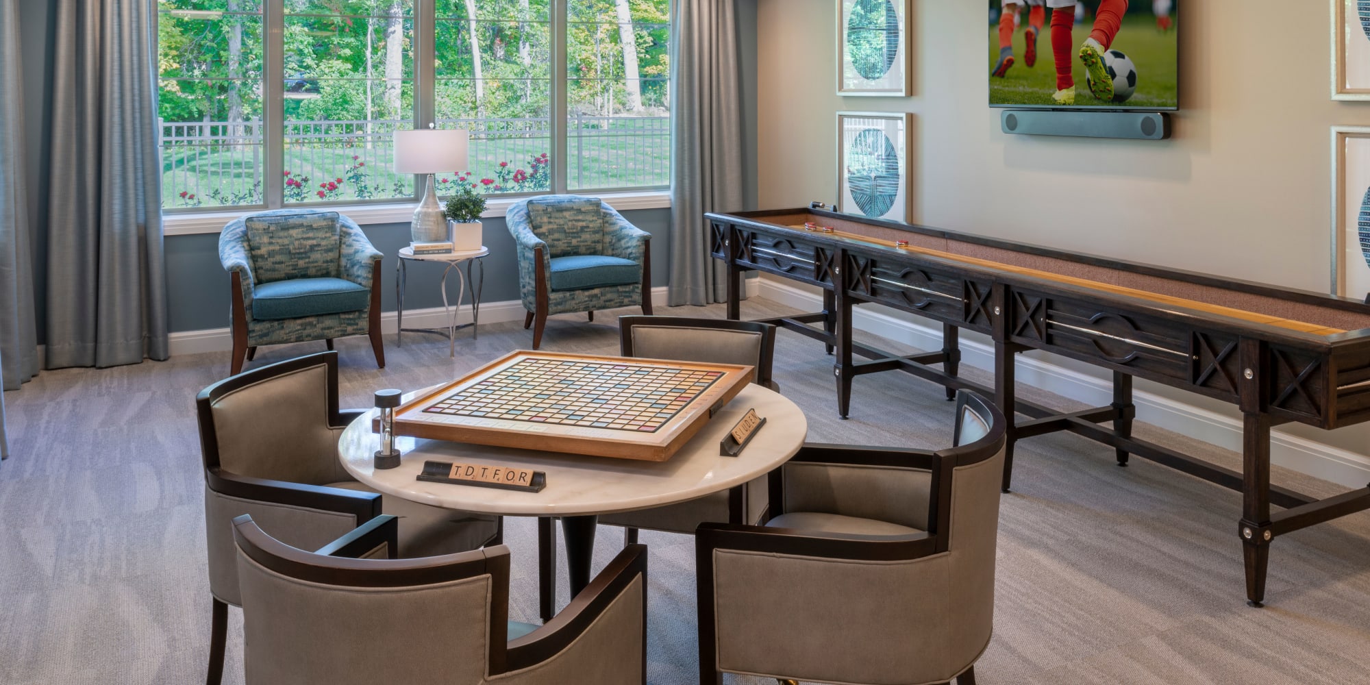 Game room with a long shuffleboard table and seating for many at Blossom Springs in Oakland Twp, Michigan
