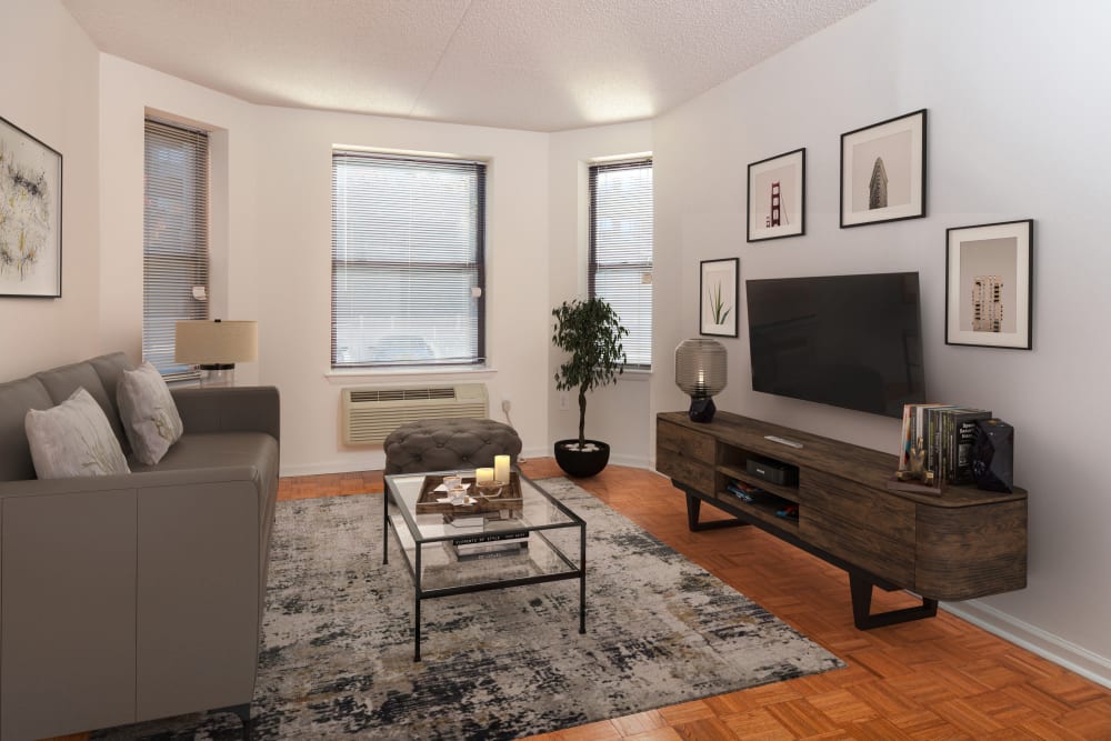 Model living room with hardwood floors and oversized bay windows at The Brunswick in New Brunswick, New Jersey