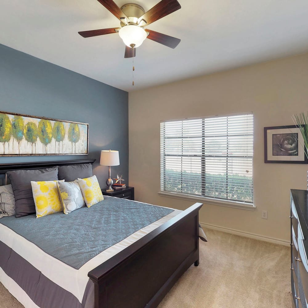 Accent wall and bay windows in a model apartment's primary bedroom at Oaks Riverchase in Coppell, Texas