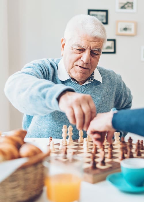 Caregiver playing chess with a resident at Grand Villa of Clearwater in Clearwater, Florida