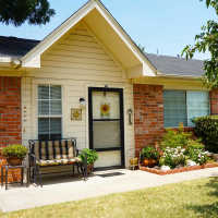 Charming entryway with lush garden and welcoming front porch at The Parc at Bakers Pointe in Richland Hills, Texas