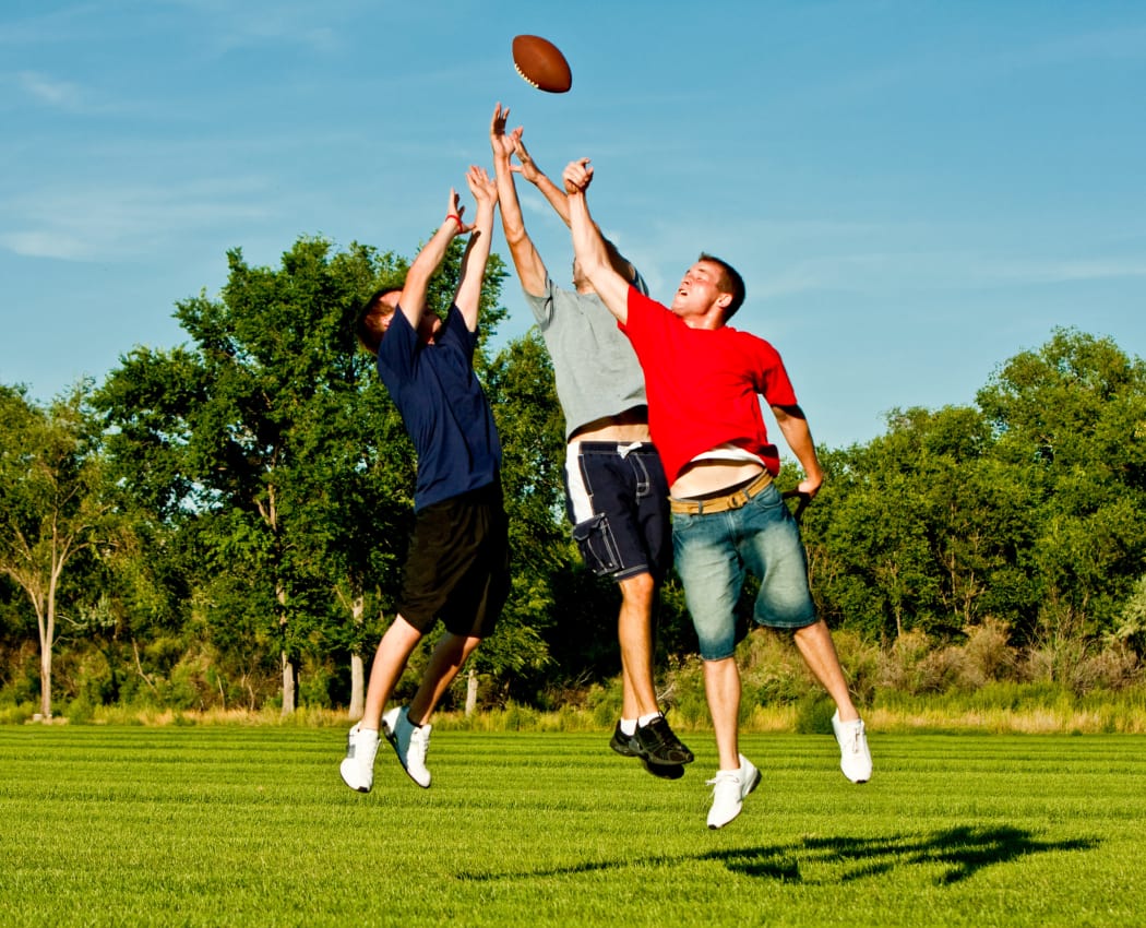 Group of friends playing football near Pin Oak Townhomes in Norman