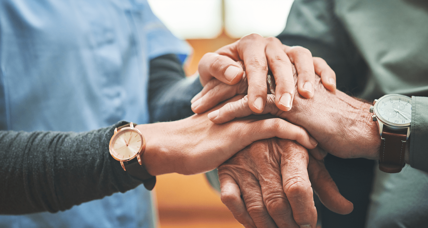 Caretaker holding hands with a resident at a Heritage Senior Living community