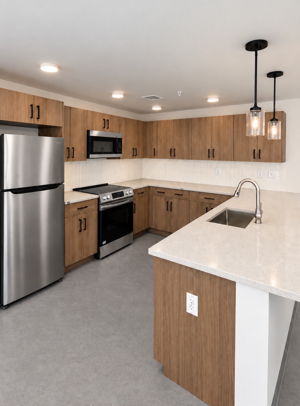 Contemporary kitchen with quartz backsplash, wood cabinets, Silver refrigerator and island sink at Altitude on Main in Richmond, Virginia