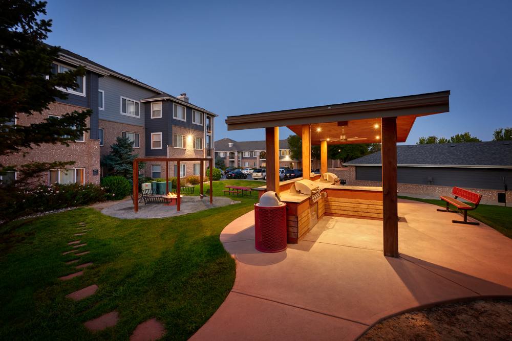 The outdoor picnic area with a firepit, swings, and BBQs at Hawthorne Hill Apartments in Thornton, Colorado