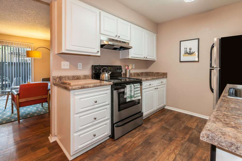 Kitchen with wood-style flooring and white cabinets at The Woodlands Apartments in Sacramento, California