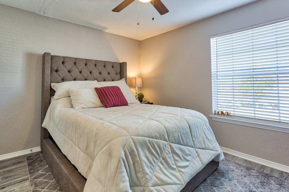 Bedroom with a large bed and ceiling fan at The Gardens At Duncan Apartments in Duncan, Oklahoma