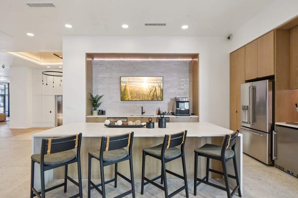 Modern kitchen with island, bar stools, and stainless appliances at Tempo at Nine Mile Station in Aurora, Colorado