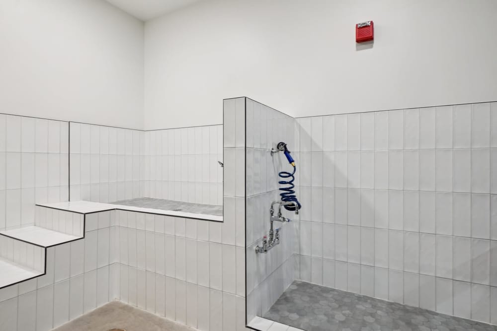 Tiled shower room with step-up platform, hose, and red wall sensor at Tempo at Nine Mile Station in Aurora, Colorado