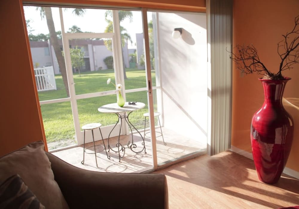 Living room with hardwood floors and view of private deck of Lime Tree Village with pool in Deerfield Beach, Florida