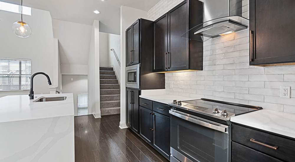 Modern kitchen with stainless-steel appliances and stairs at Domain Memorial in Houston, Texas