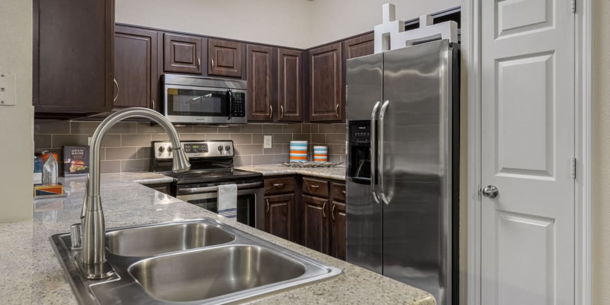 Modern kitchen with granite counters and stainless steel appliances at Marquis at Kingwood in Kingwood, Texas