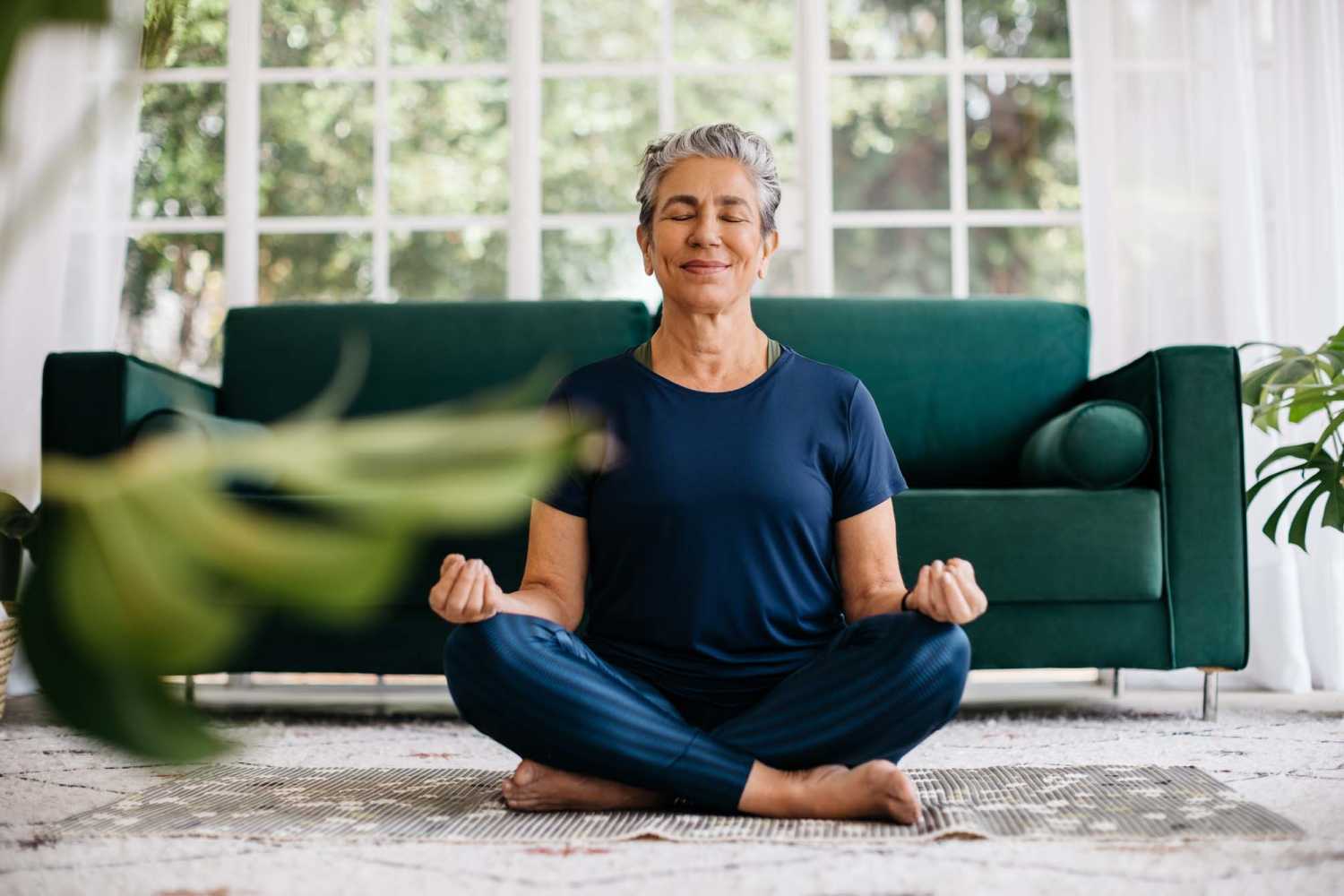 Senior woman practicing yoga in her living room at Ellsworth Commons Apartments in Greenville, North Carolina