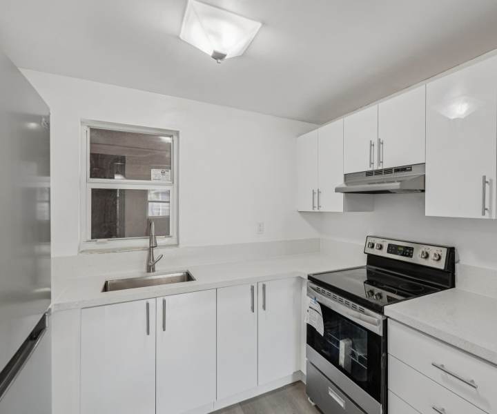 Stainless-steel appliances and white cabinets in the kitchen at El Jardin Apartments in Hollywood, Florida